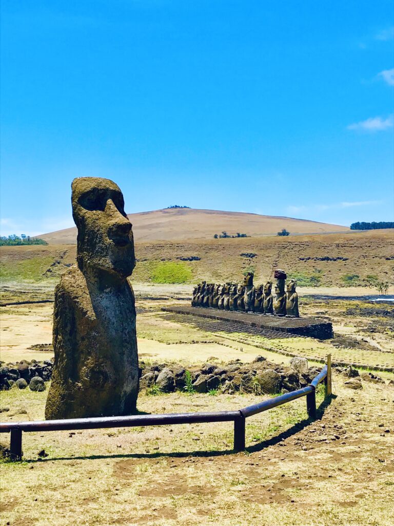 Zbliżenie z profilu na rząd potężnych posągów moai ustawionych na platformie Ahu Tongariki pod czystym niebem na Wyspie Wielkanocnej.