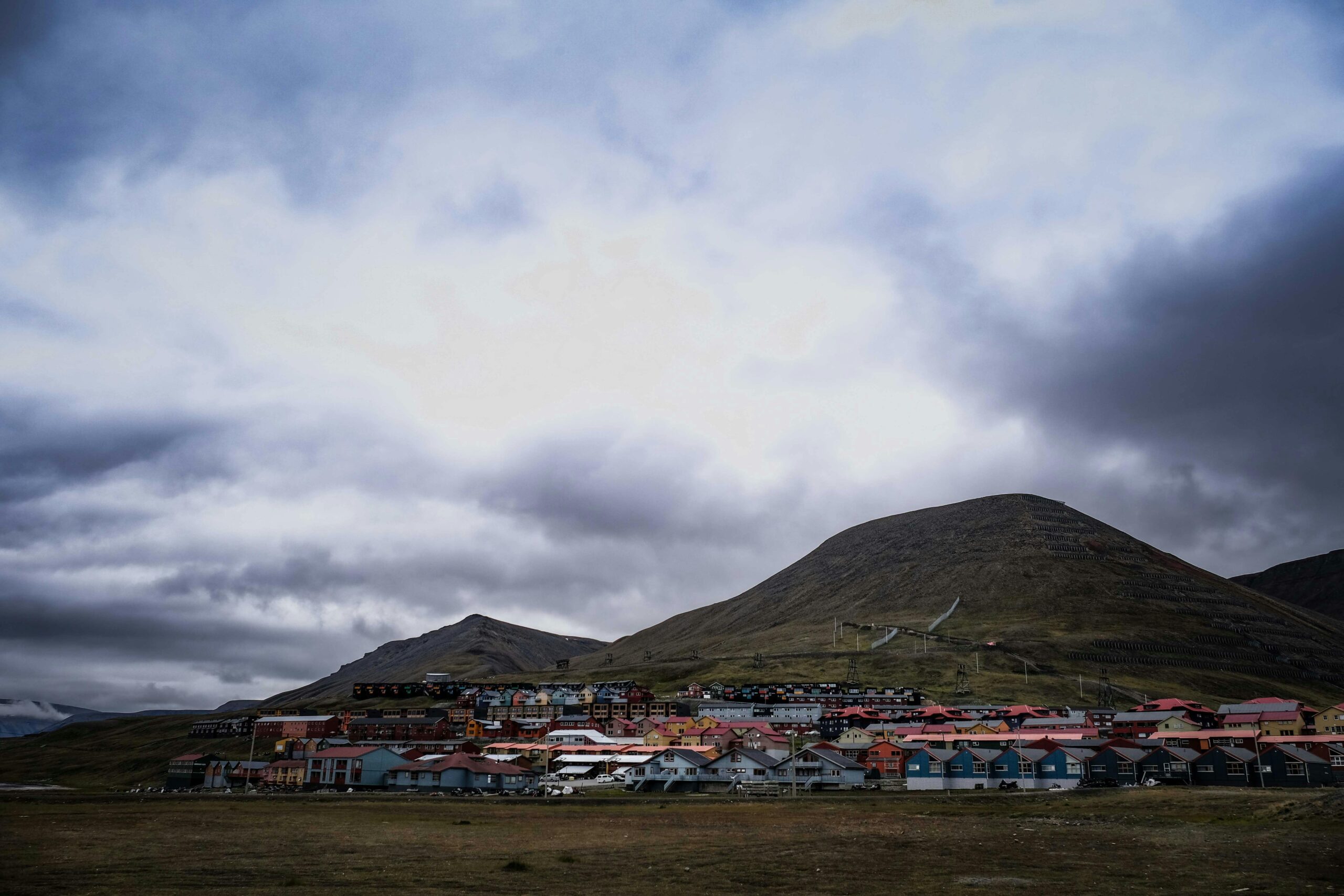 Panorama Longyearbyen latem Kolorowe domy osady Longyearbyen u podnóża surowych, ciemnych gór pod zachmurzonym, arktycznym niebem.